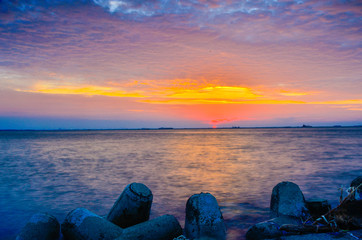 Enjoying beautiful colorful peaceful calm sunset at the horizon at a waterfront shorefront of Pantai Mutiara Jakarta Indonesia