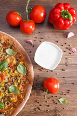 Vegetarian pizza and ingredients with spices on board, fast food concept