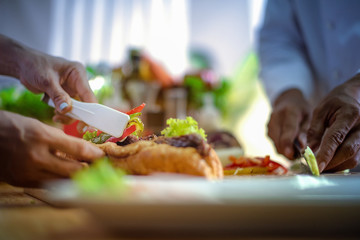 assorted fried vegetable sliced tong by hand of chef laying on french bread with meat layer on the bread, chef cooking homemade for members serving in new and always fresh