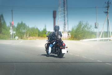 Sexy biker female in black leather jacket and helmet sit on vintage big black motorcycle. Traveling and active hipster lifestyle. Girls power.