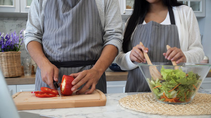 The spouses are cooking in the kitchen