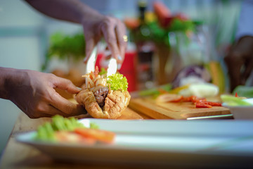 assorted fried vegetable sliced tong by hand of chef laying on french bread with meat layer on the bread, chef cooking homemade for members serving in new and always fresh