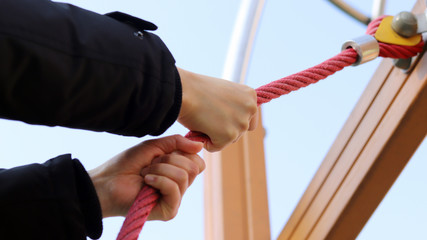 A hand holding on to a red rope.