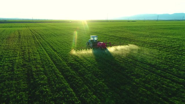 Aerial view of farming tractor plowing and spraying on field