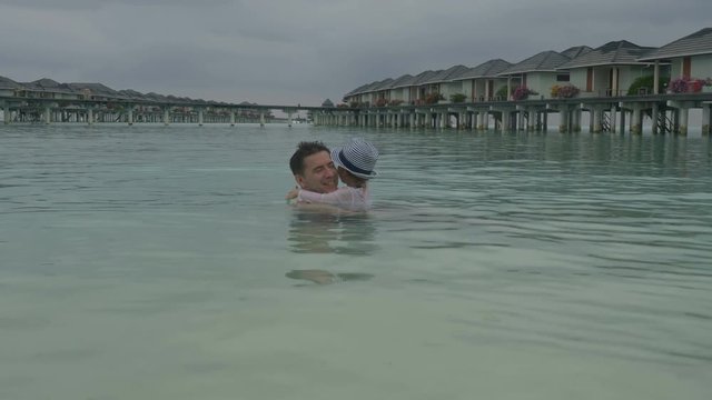 Dad and his daughter swim in the sea.