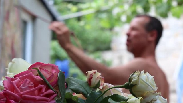 Portrait Of Male Artist Working On Painting In Outdoors Studio.Bouquet of roses in the open air
