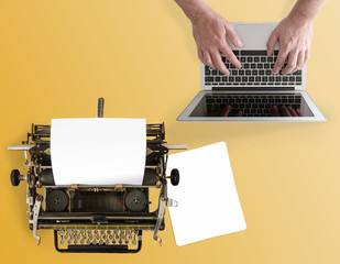 top view of vintage manual typewriter and man typing on notebook computer on desk