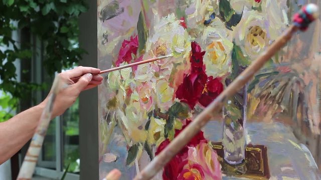 Artist with brushes and tools. Oil painting master class. A work of art. Bouquet of roses in the open air. Sammer