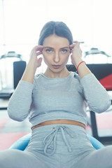 Young fit and beautiful sportswoman is exercising on the mat indoors.