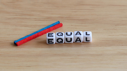 EQUAL text cube and two color stick on the wood background.