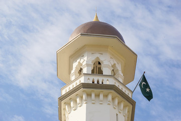 Minaret with flag of Islam on blue sky. Mosque Penang, Malaysia