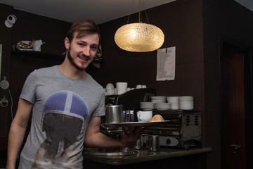 waiter serving coffee and croissant on tray