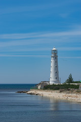 Fototapeta na wymiar seascape with beautiful white lighthouse on blue sky background.