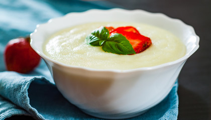 bowl of Semolina porridge with strawberries on wooden table