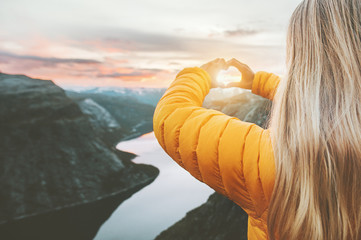 Hands heart love symbol shaped woman traveling lifestyle charity help concept vacations in Norway sunset mountains and lake landscape
