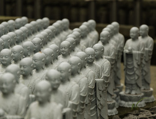 Statue of budhist monks standing seating praying meditating in a temple in Japan Asia
