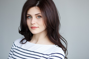 A beautiful brunette girl with cute green eyes,clean skin,wavy hair with volume looks at camera...