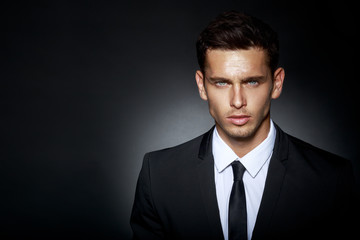 Portrait of a bussines man, wearing in black elegant suit looking at camera, isolated on black background. Horizontal view.
