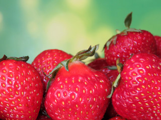 Ripe strawberries with leaves on a blurred green background. A lot of fresh red strawberries close-up