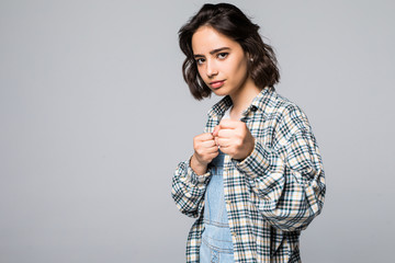 Portrait of confident woman model standing in boxer pose with raised fists as if wanting to attack someone, saying come on over gray background.