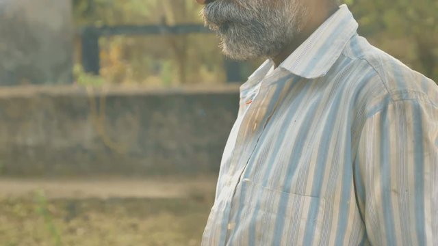 A working farmer taking a break to make payment of seed purchasing using Credit or Debit card while water well in the back. A male middle aged man using ATM card to pay by smartphone or cellphone