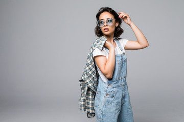 Naklejka premium Confident young casual woman looking at camera through sunglasses isolated on a gray background