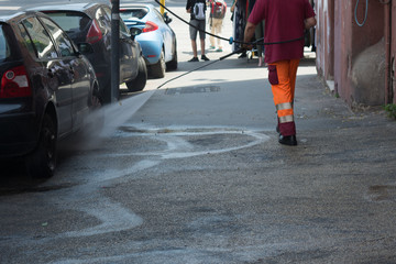 Horizontal View of a Dustman Cleaning the Street With a Water Pressure Machine