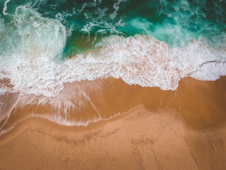 Sand beach aerial, top view of a beautiful sandy beach aerial shot with the blue waves rolling into the shore
