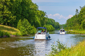 Motorboats on a canal in an idyllic summer landscape