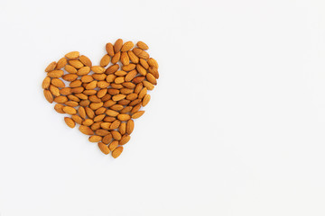 Almonds laid out in the shape of a heart on a white background. Top view, copy space