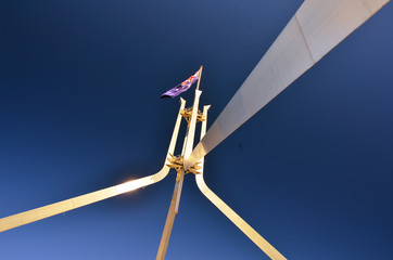 Australian flag on top of tower steel building of parliament house in canberra under bright blue warm and sunny sky