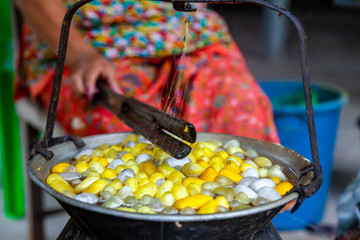 Close Up Hand of Woman Worker Boiling White and Yellow silkworm cocoons in the pot to make Silk...