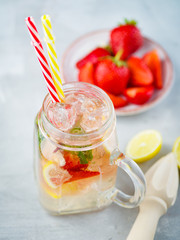 Ice fizzy Strawberry lemonade with mint and lemon in Mason jar.