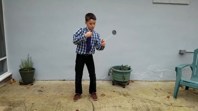 Boy performs yoyo tricks on concrete patio
