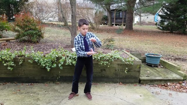 Boy performs yoyo tricks in backyard
