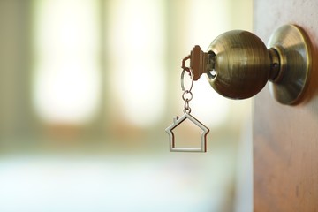 Home key with house keychain in keyhole, property concept