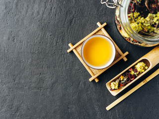 Obraz na płótnie Canvas Freshly brewed Herbal tea. Wooden spoon. Glass jar with tea leaves.Dark concrete stone background.