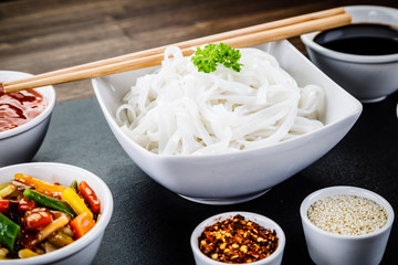Rice noodles and vegetables on wooden background