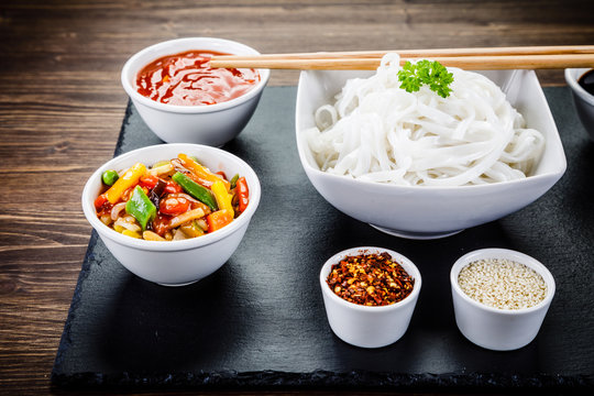 Rice noodles and vegetables on wooden background