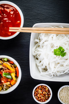 Rice noodles and vegetables on wooden background