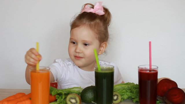 Girl child drinks vegetable smoothies - Carrot, beet and green. Detox.
