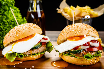 Tasty burgers with chips served on cutting board