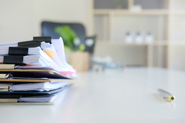Stack of paper files and pen business equipment on office table.