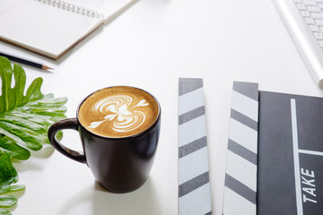 Office stuff with Movie clapper laptop and coffee mug pen notepad on the white table top view shot.