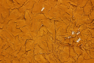 Texture or background, cracks on a yellow-orange paint on a concrete wall