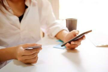 Closeup woman using credit card and smartphone for shopping online.