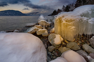 Russia. mountain Altai. Evening light in ice floods and icicles on the shore of lake Teletskoye.