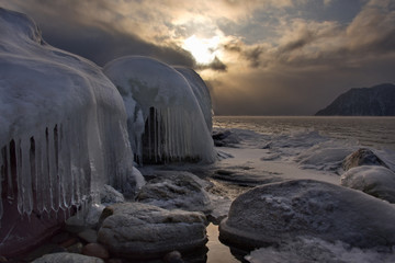 Russia. mountain Altai. Evening light in ice floods and icicles on the shore of lake Teletskoye.