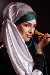 close-up photo of Muslim female putting on makeup in the spa center. put up make up befor the party