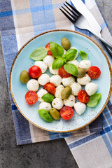 Delicious caprese salad with ripe cherry tomatoes and mini mozzarella cheese balls with fresh basil leaves.